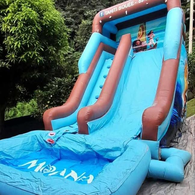 Toboggan gonflable bleu Vaiana installé dans un jardin à Tahiti